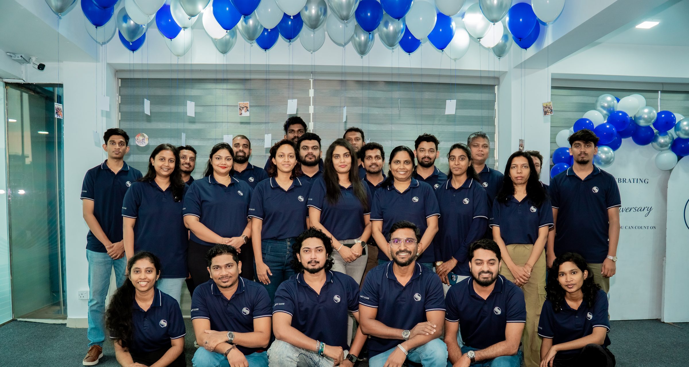 The Swiftcore team, around thirty people in navy company polos, gathered for a group photo in the office